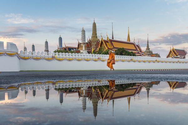Temple of the Emerald Buddha spires and Grand Palace wall reflected in a puddle in Bangkok, Thailand