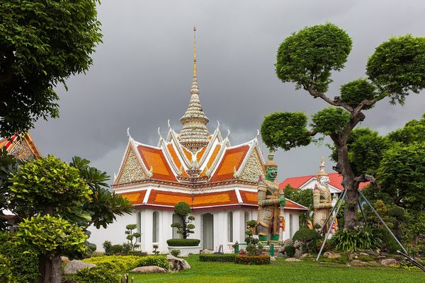Orange-roofed pavilion and trimmed trees in the grounds of Wat Arun in Bangkok, a temple setting for November events