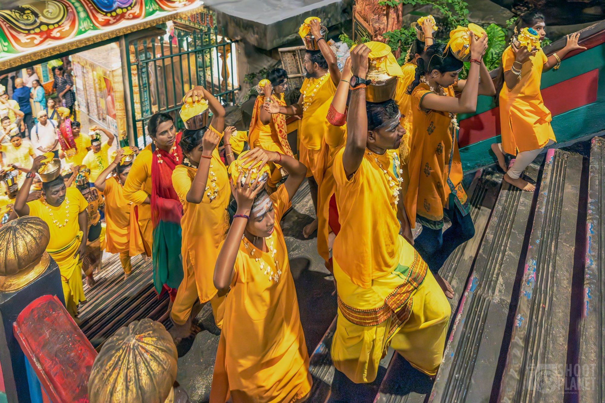 Penganut berpakaian kuning membawa periuk susu di atas kepala menaiki tangga Batu Caves