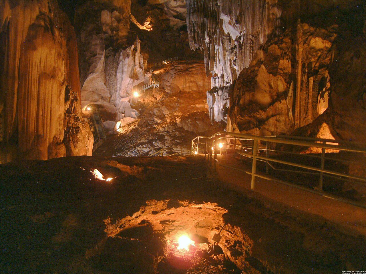 Lit walkway and orange-lit stalactites inside Gua Tempurung cave