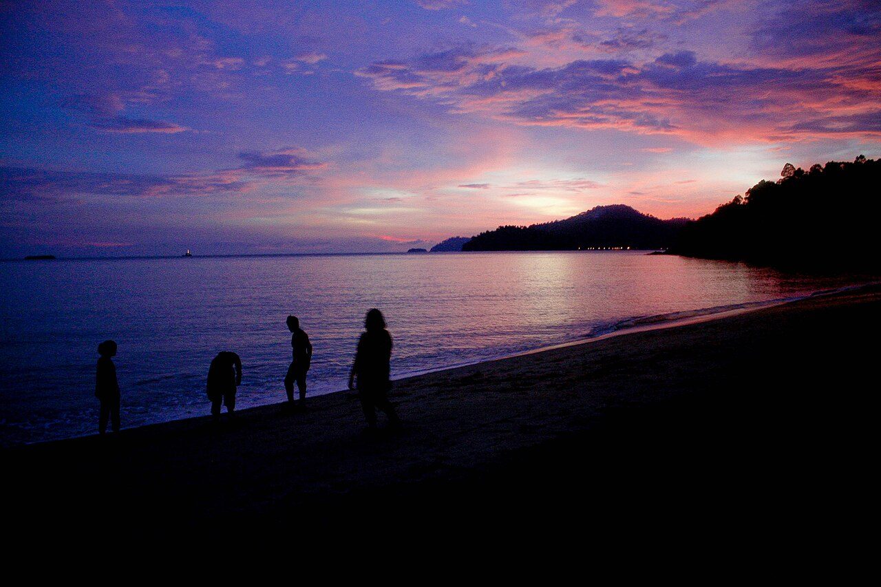 Beaches and islands near Ipoh: dusk over the sea at Teluk Batik with people walking on the sand