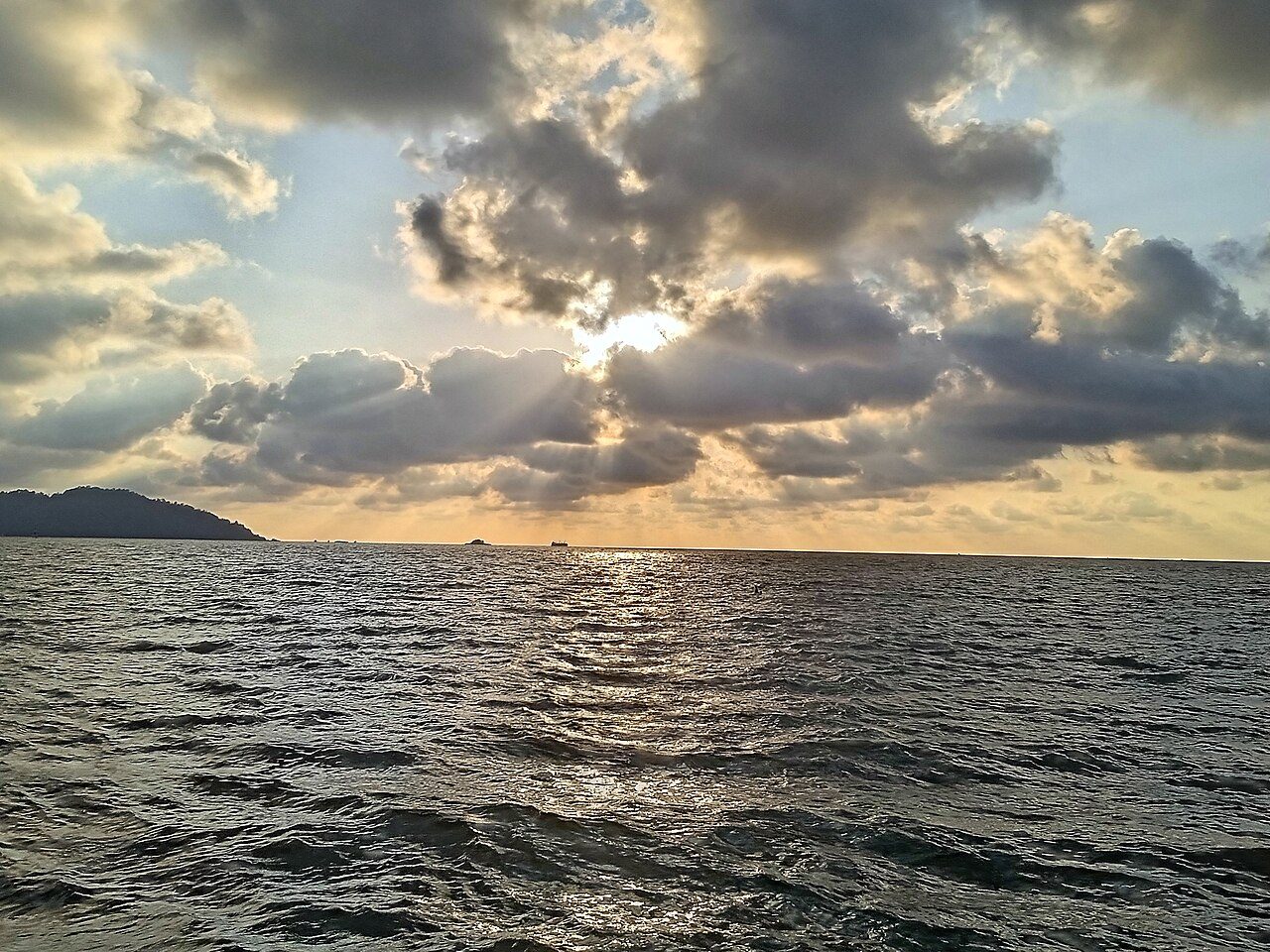 Late sun breaking through clouds over the sea at Teluk Senangin