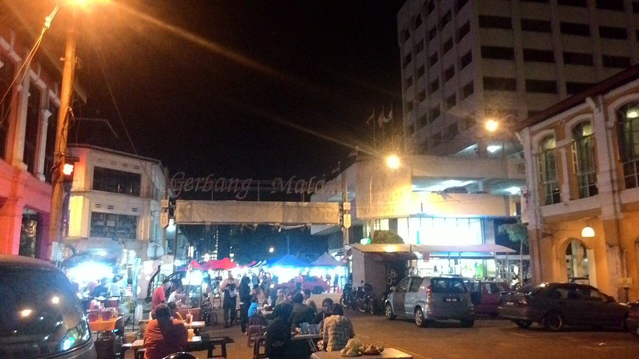 Gerbang Malam arch over a street of stalls and diners at night, one of the night markets in Ipoh