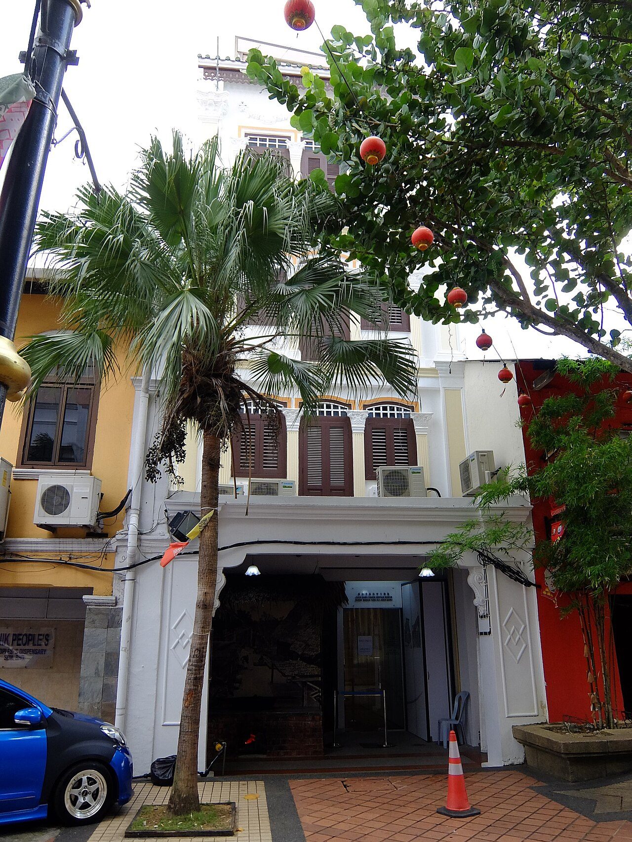 The white four-storey shophouse of the Johor Bahru Chinese Heritage Museum on Jalan Ibrahim, with red lanterns in a tree outside