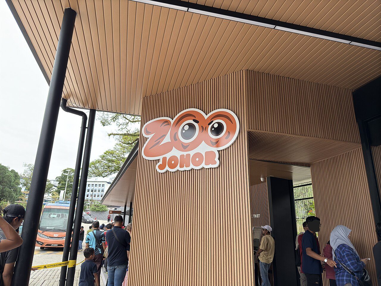 The new timber-clad entrance building of Zoo Johor with its cartoon logo and visitors queuing at the ticket counter