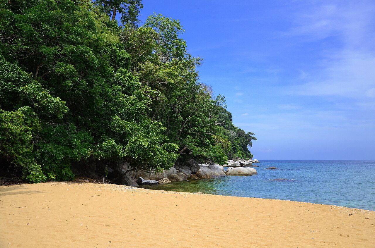 A quiet cove of golden sand at Pulau Tioman with forest down to granite boulders and clear blue water