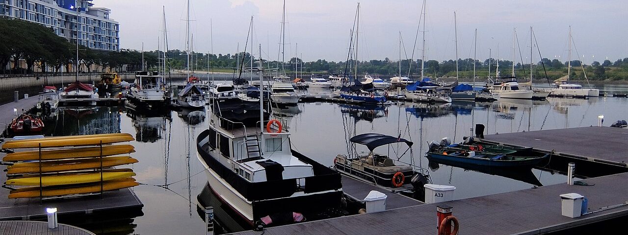 Yachts and motor boats moored at the Puteri Harbour marina in Iskandar Puteri, with a low-rise waterfront building on the left at dusk