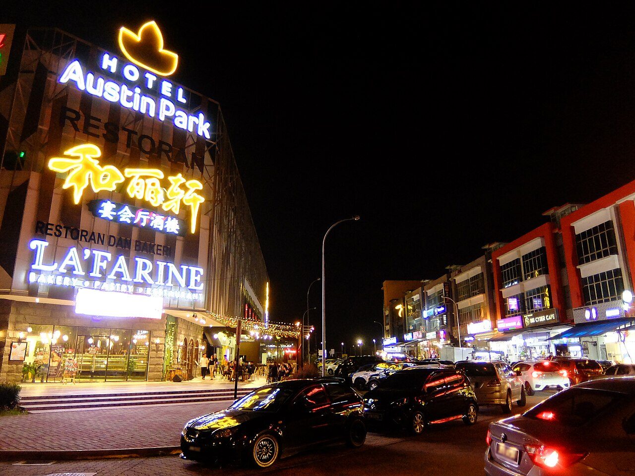 Mount Austin at night with lit shop signs and a row of shophouses, the Johor Bahru suburb with the most dessert cafes in this guide