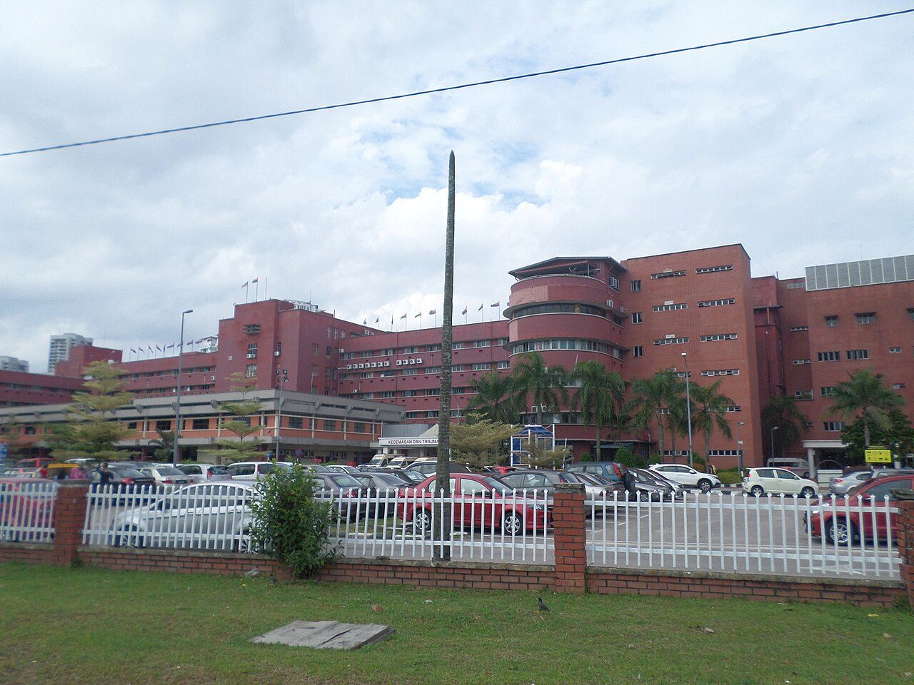 Johor Bahru hospitals: the red-brick blocks of Hospital Sultanah Aminah behind a car park, with the Kecemasan dan Trauma (Emergency and Trauma) entrance in the centre