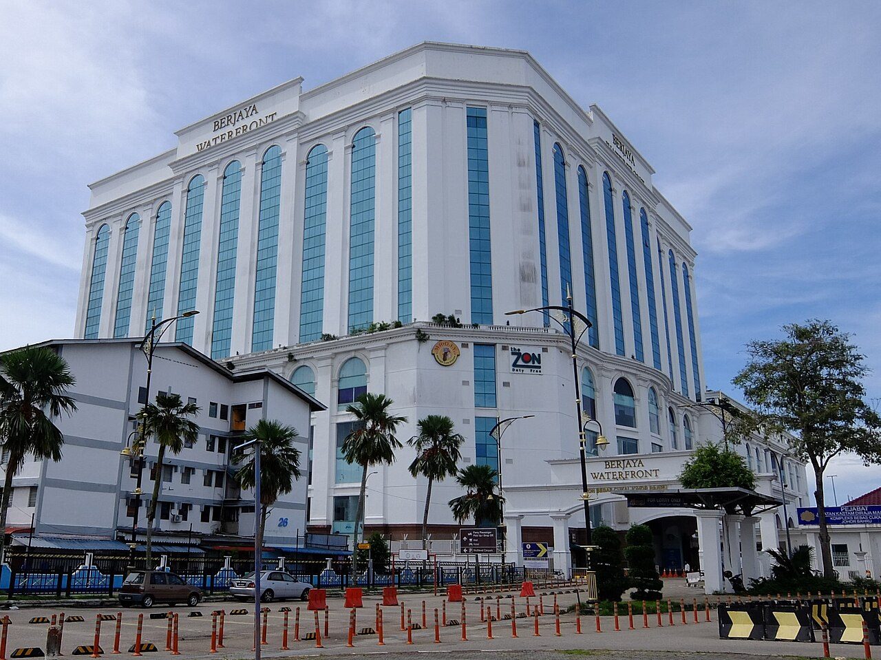 Berjaya Waterfront Hotel, a white building with tall arched blue windows and The ZON duty-free sign, at Stulang Laut