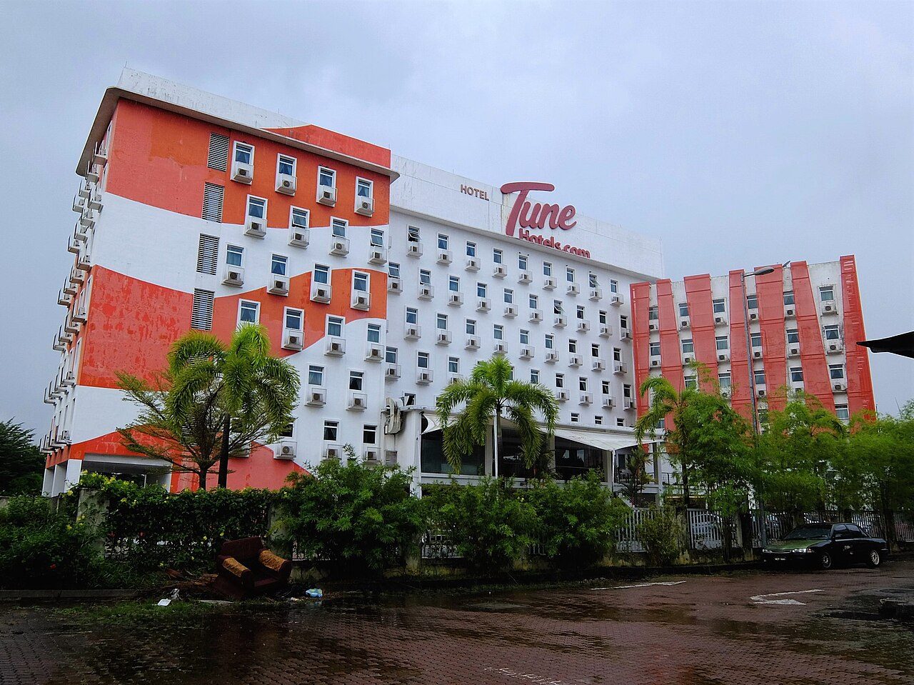 Tune Hotel Danga Bay, a seven-storey budget hotel painted in orange and white stripes with palm trees in front