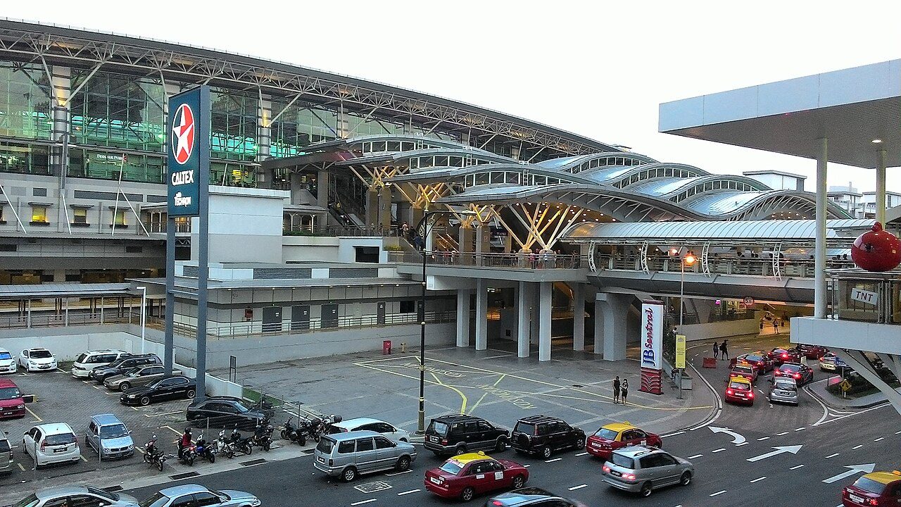 Money changers in Johor Bahru: the JB Sentral station building and its roof canopies seen from the bridge to City Square, with taxis and cars below