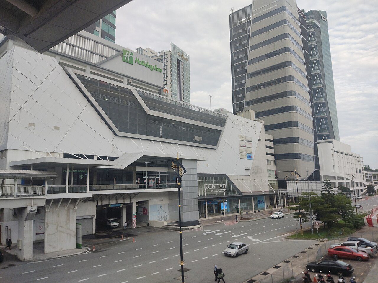 The white angular facade of the Komtar JBCC mall and the Komtar tower behind it, seen from an elevated walkway above Jalan Wong Ah Fook