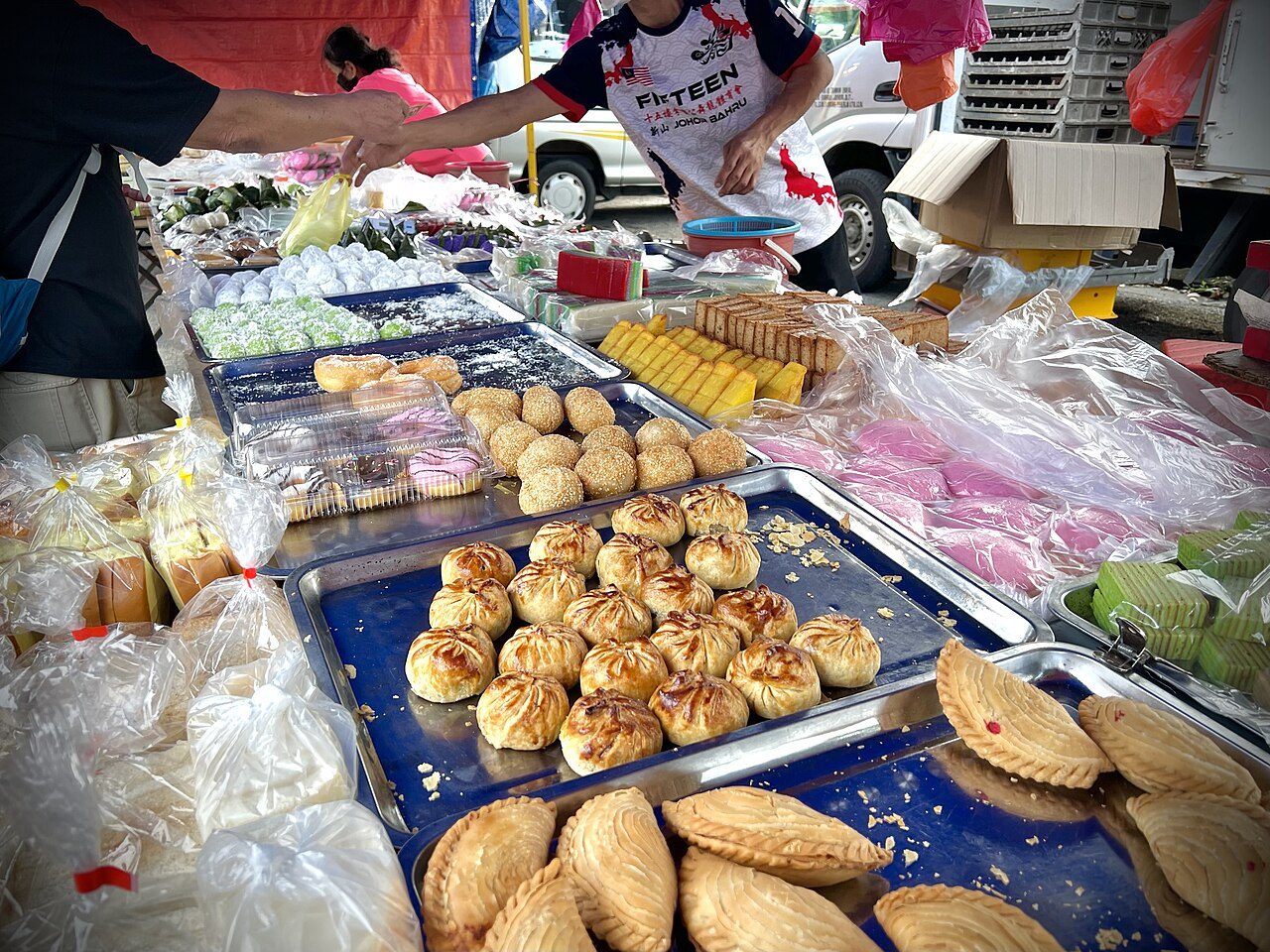 Trays of curry puffs, sesame balls and kuih on a stall at the Bukit Indah 2 Wednesday market, one of the night markets in Johor Bahru, photographed in 2023