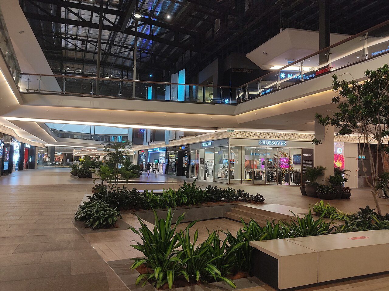 Inside Mid Valley Southkey: a wide mall walkway with planters, shopfronts and a glass roof above two upper floors