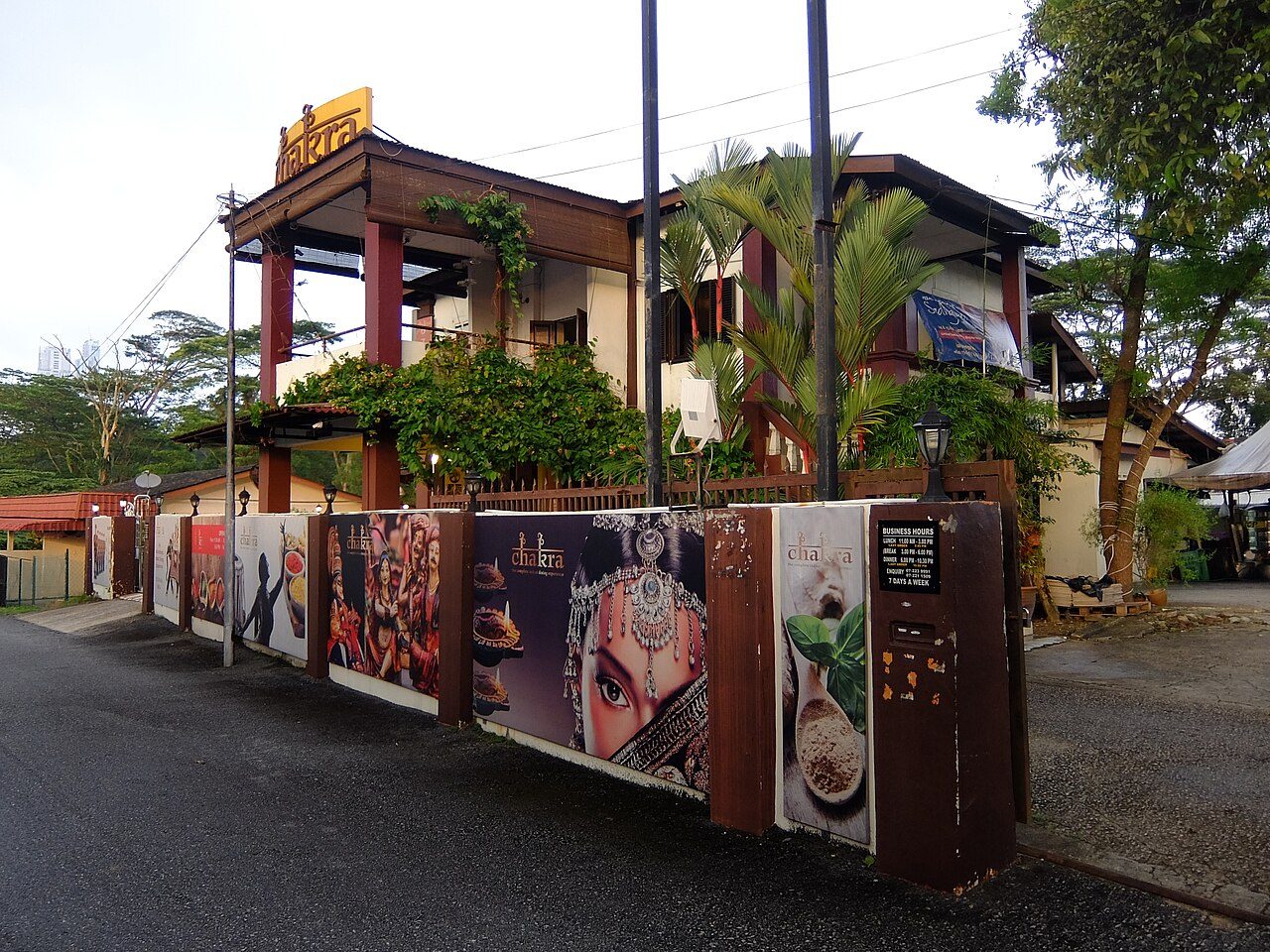 Chakra Restaurant in Kampung Bahru, Johor Bahru, a two-storey bungalow with red pillars behind a fence painted with Indian food and dance images
