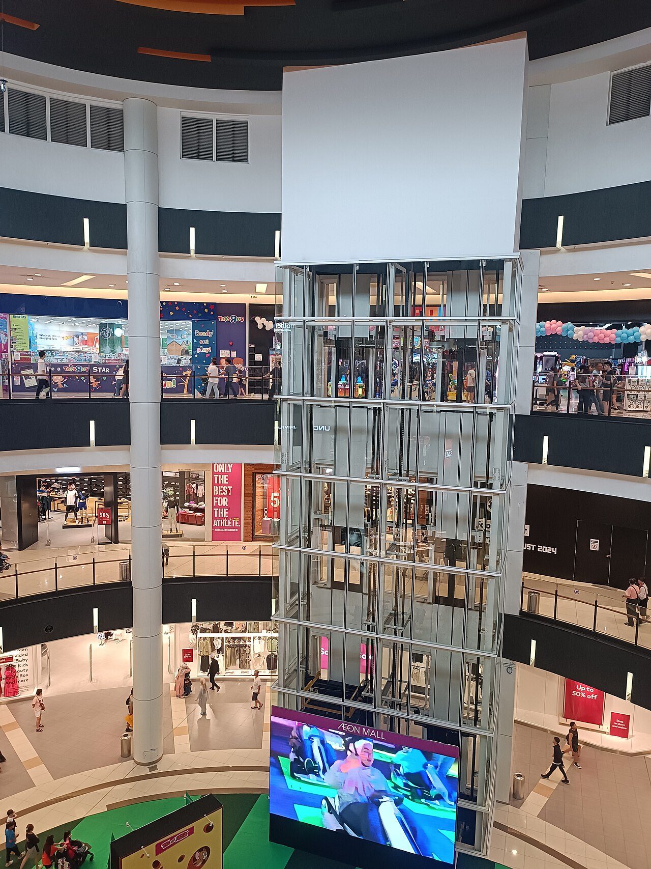 Inside AEON Mall Tebrau City, with a glass lift shaft rising through the round atrium and shop floors around it