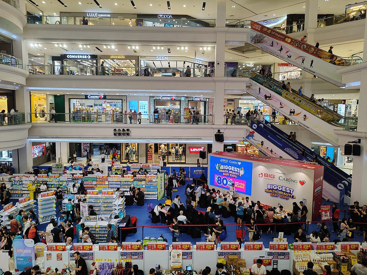 Escalators and shop floors around the atrium of Johor Bahru City Square, with shoppers at a sale on the ground floor