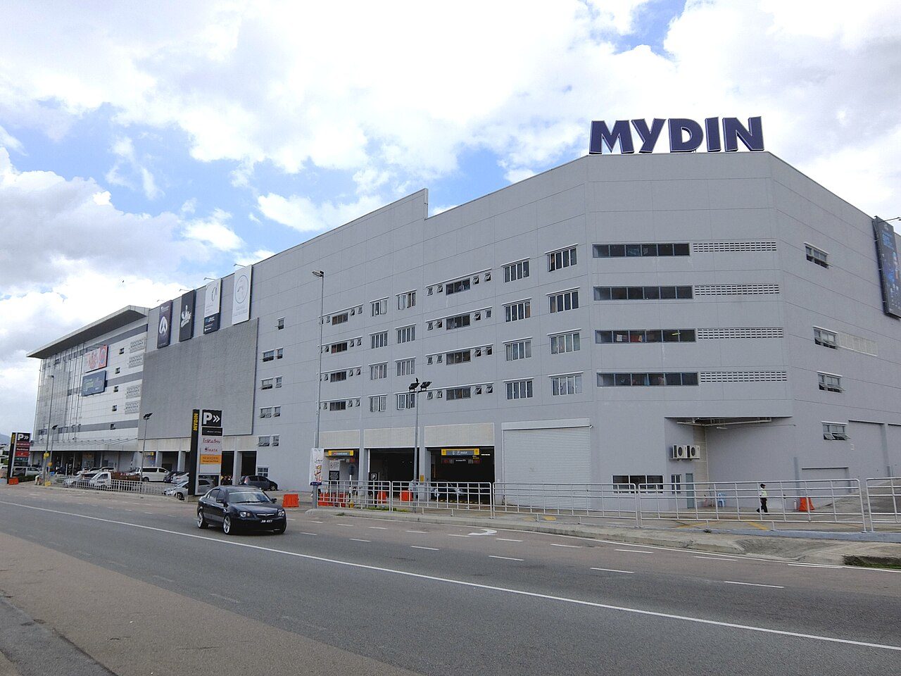 Mydin Mall in Mutiara Rini, Skudai, home to one of the big supermarkets in Johor Bahru: a long grey building with a dark blue MYDIN sign on the roof and a car on the road in front
