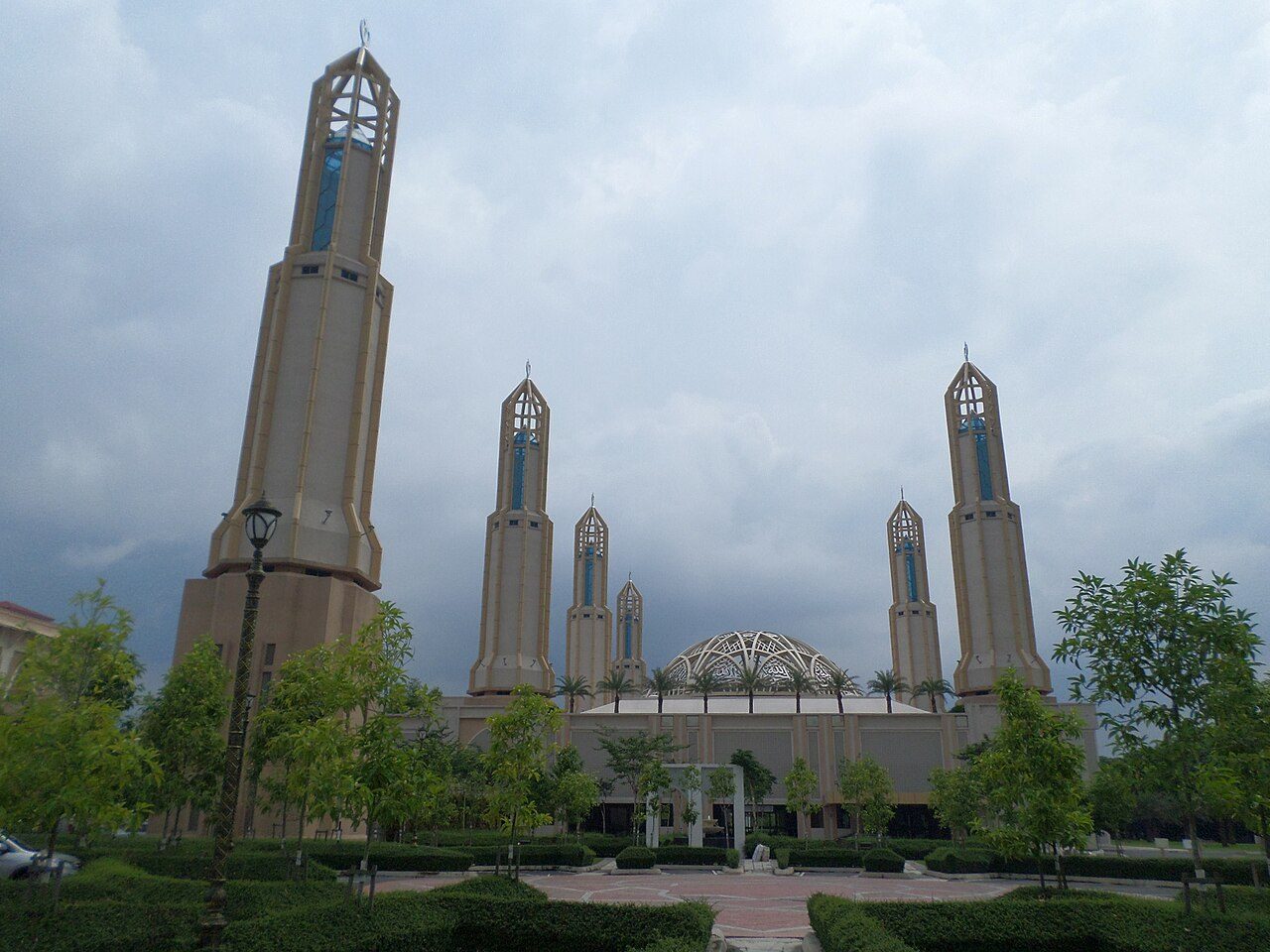 The Mosque of Kota Iskandar with its tall pale minarets and a latticed dome behind landscaped gardens
