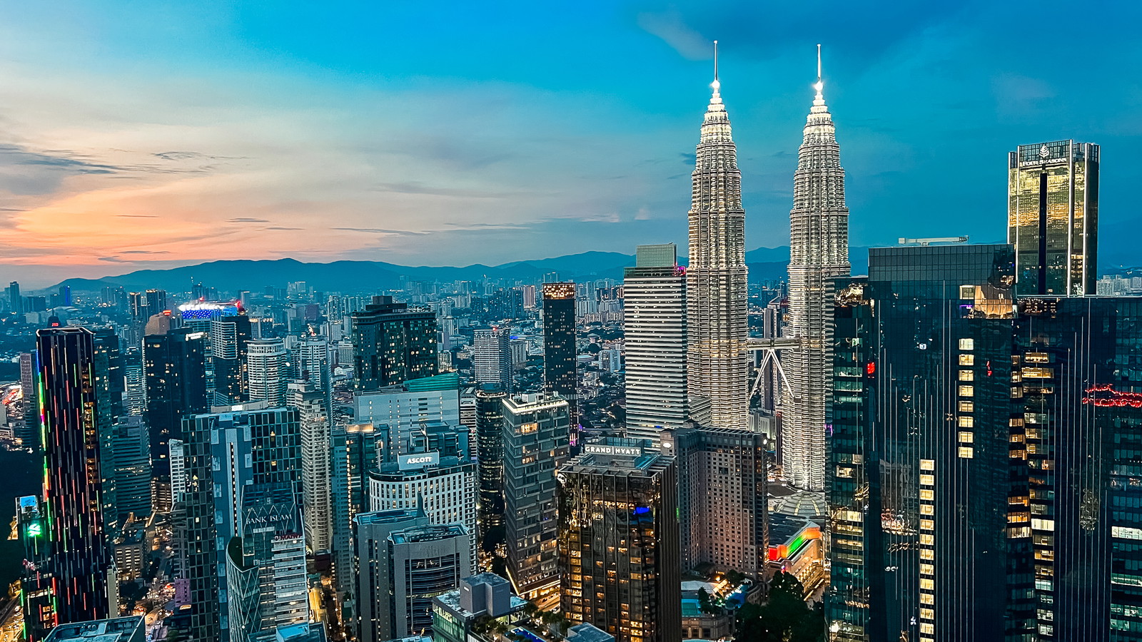 Tempat wisata Kuala Lumpur: cakrawala kota saat matahari terbenam dengan Menara Kembar Petronas menjulang di atas kota