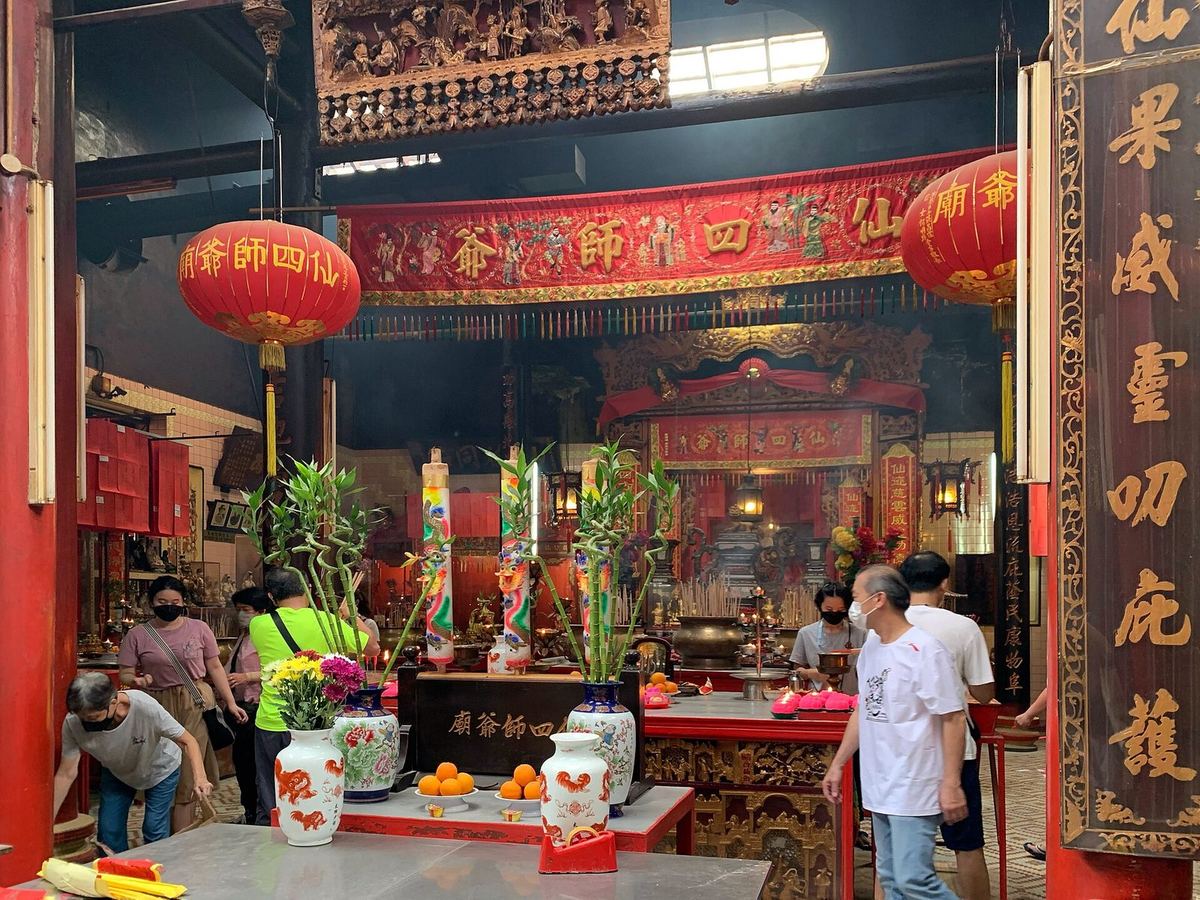 Worshippers at the red and gold altar inside Sin Sze Si Ya Temple, Chinatown, Kuala Lumpur