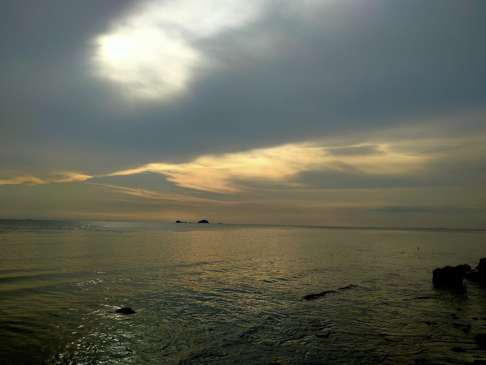 从Jeram的Pantai Remis眺望平静的马六甲海峡日落，地平线上有几座小岛