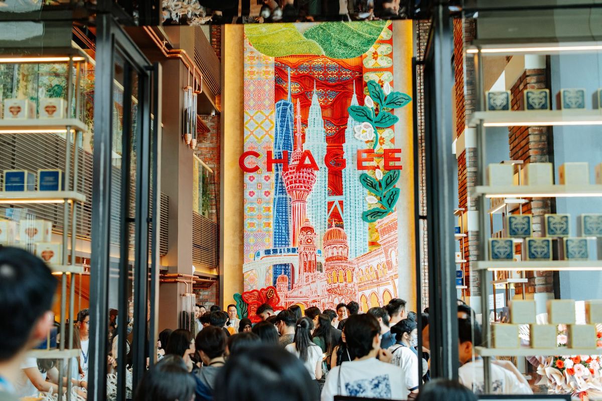 武吉免登 CHAGEE WOLO KL 旗舰店内的人群，头顶是艺术家 Afi Sulaiman 创作的吉隆坡天际线文化墙