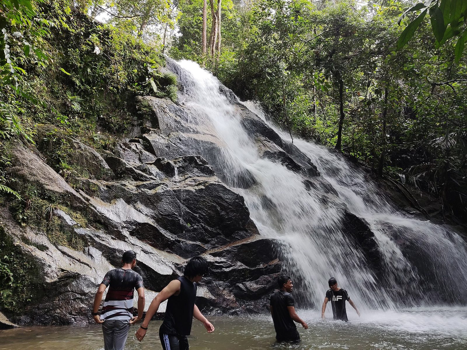Pengunjung berdiri di kolam di bawah salah satu tingkat Kanching Falls di hutan hujan dekat Rawang