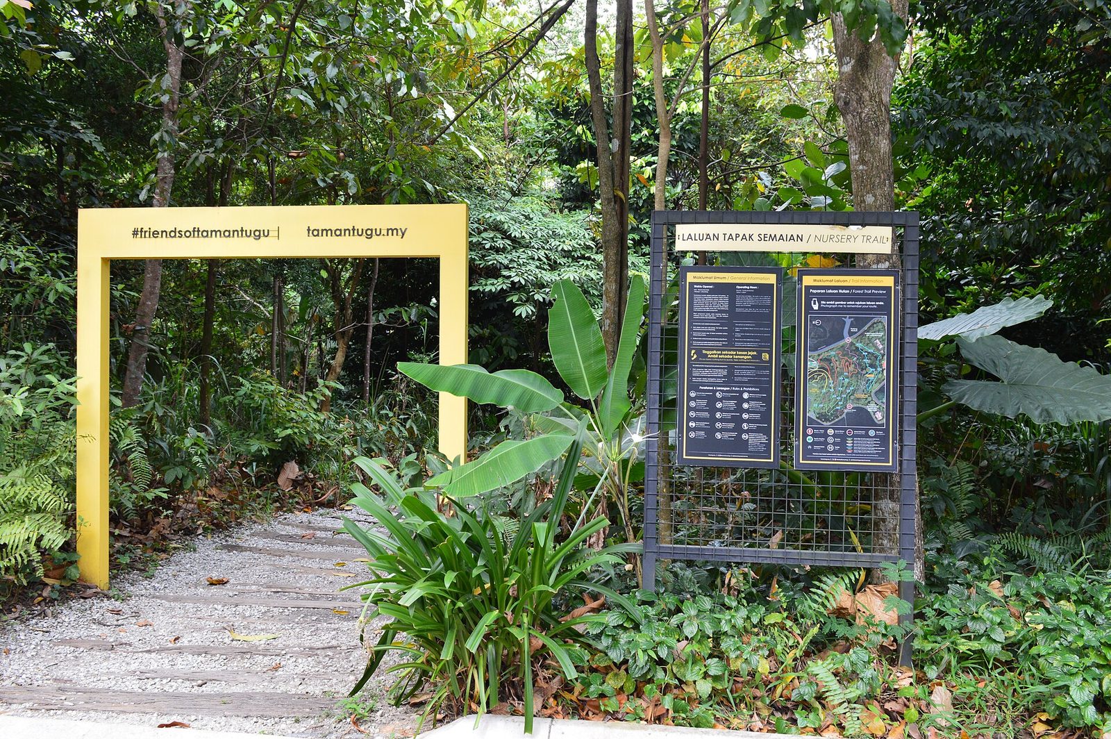 Bingkai pintu masuk kuning dan peta jalur di awal Nursery Trail di Taman Tugu, Kuala Lumpur