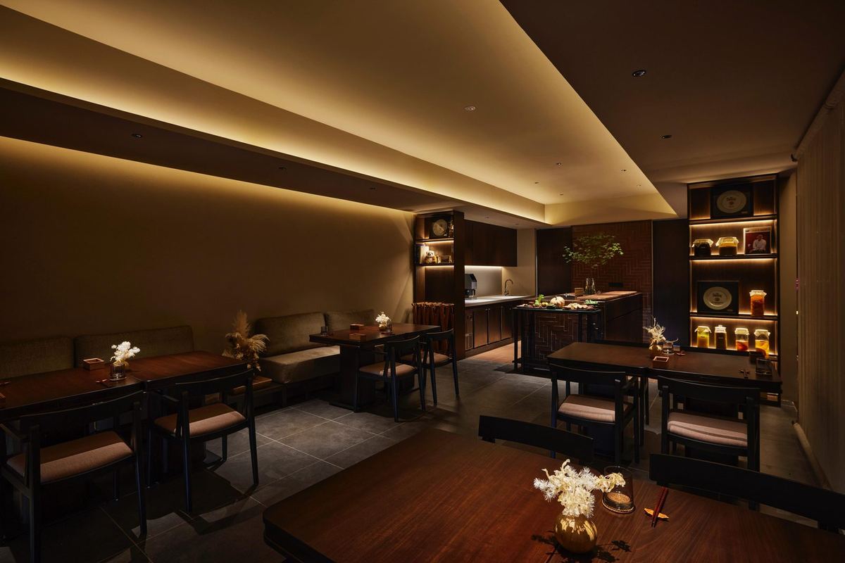 吉隆坡敦依斯迈花园 Akar 餐厅内，深色木质用餐区配以温暖的灯槽照明