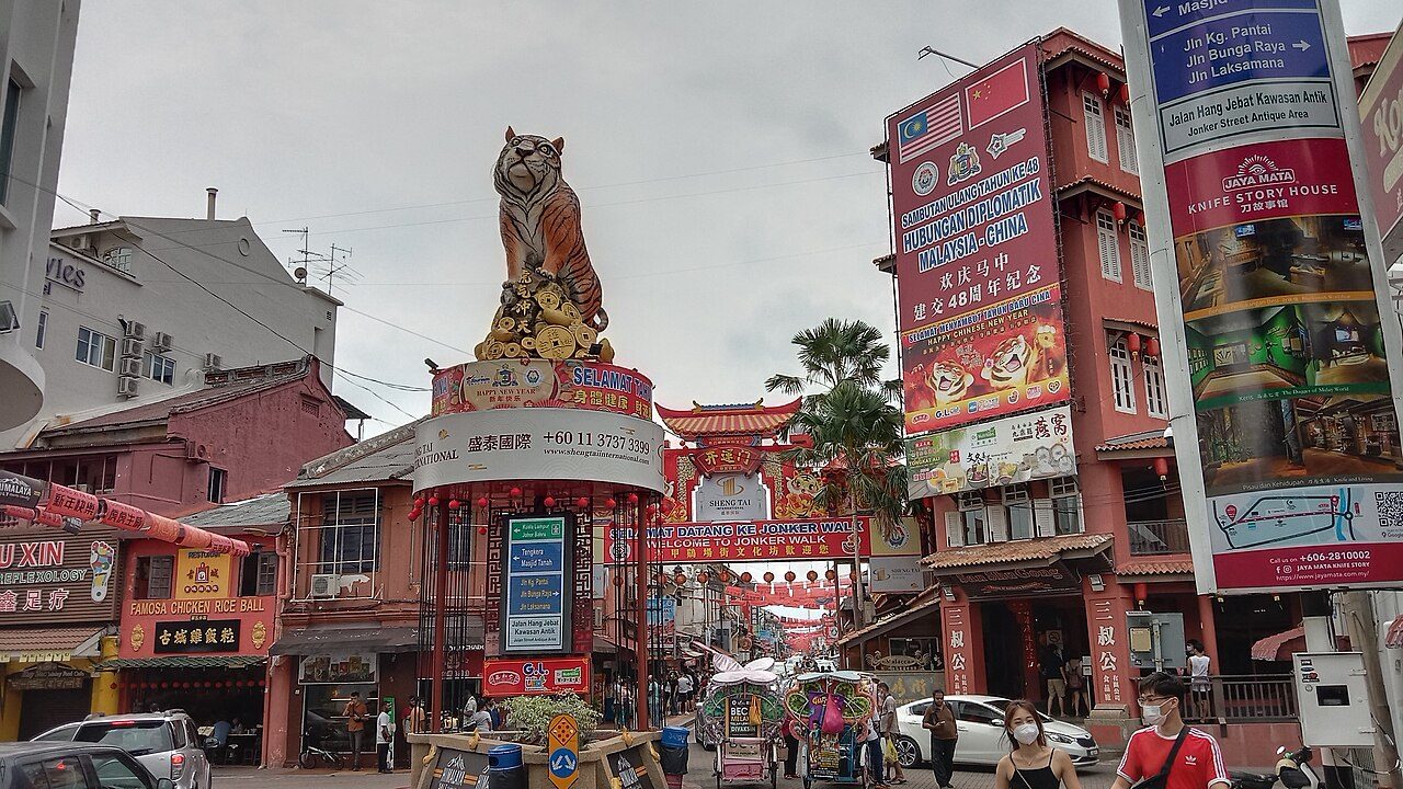 The entrance to Jonker Walk in Melaka with a tiger statue on a column and red Chinese shophouses