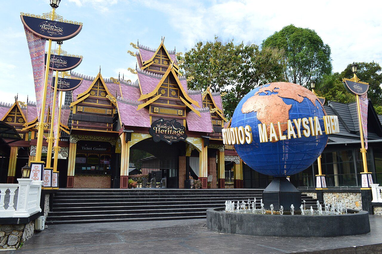 The entrance plaza of Malaysia Heritage Studios with a large blue globe and traditional Malay-style roofs