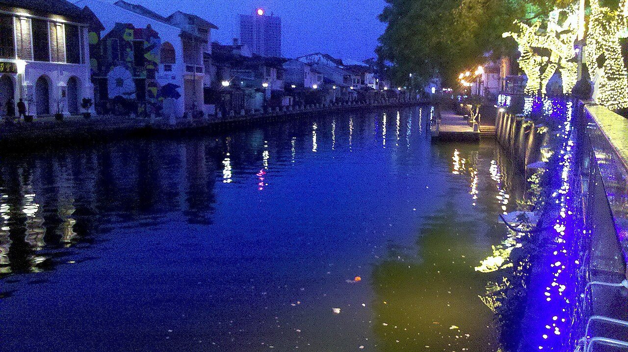 The Melaka River at dusk, with lit walkways and old houses reflected in the water, one of the things to do in Melaka