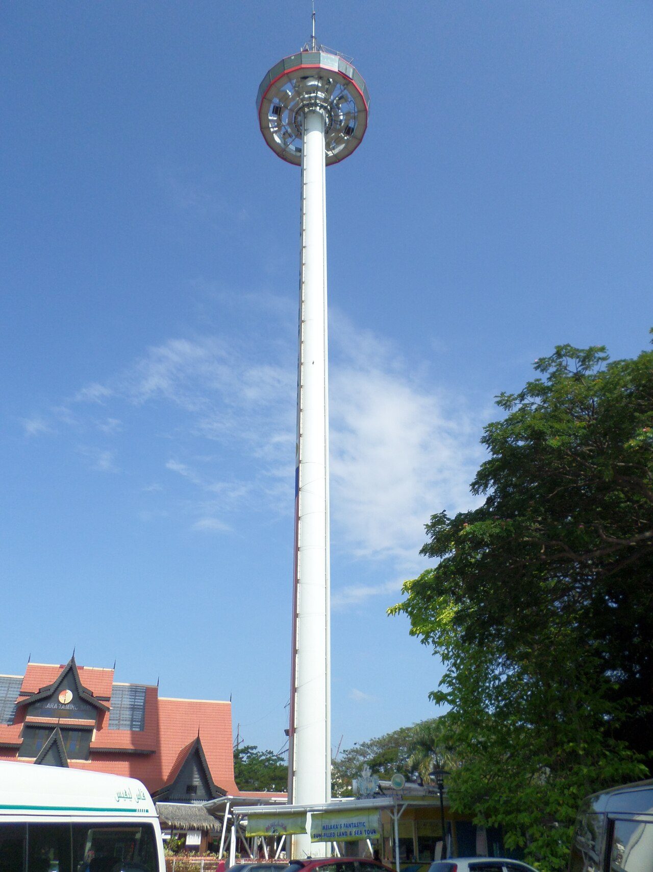 The tall white column of Menara Taming Sari tower with its viewing cabin at the top against a blue sky