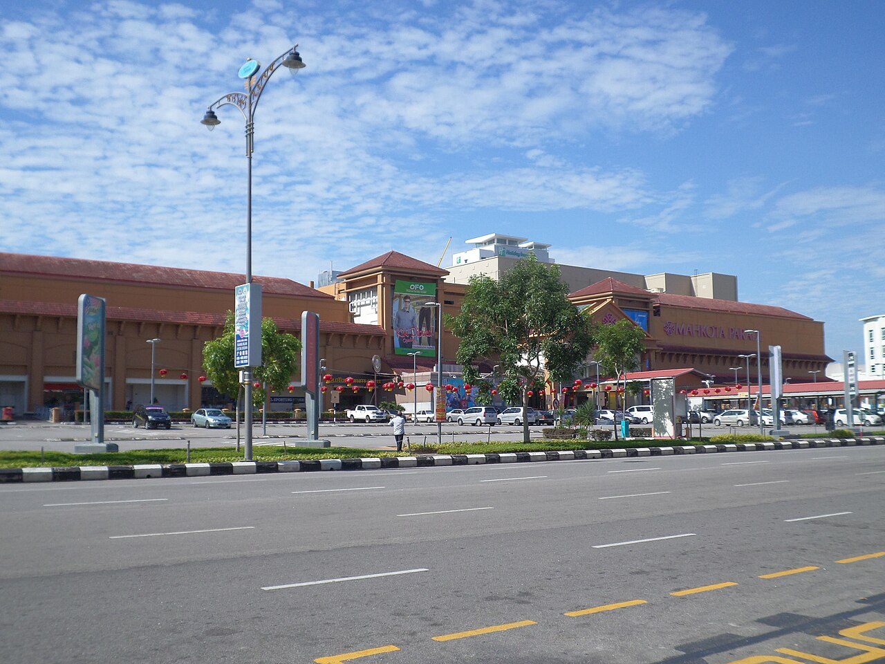 Mahkota Parade shopping centre in Bandar Hilir seen across Jalan Merdeka, with its orange facade and a car park in front