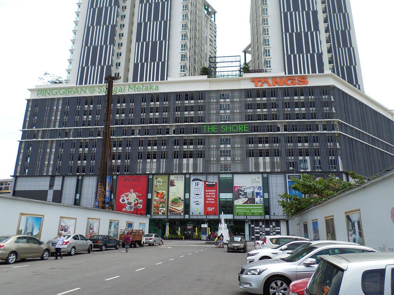 The Shore building in Melaka, with twin residential towers above a podium carrying The Shore and Tangs signs