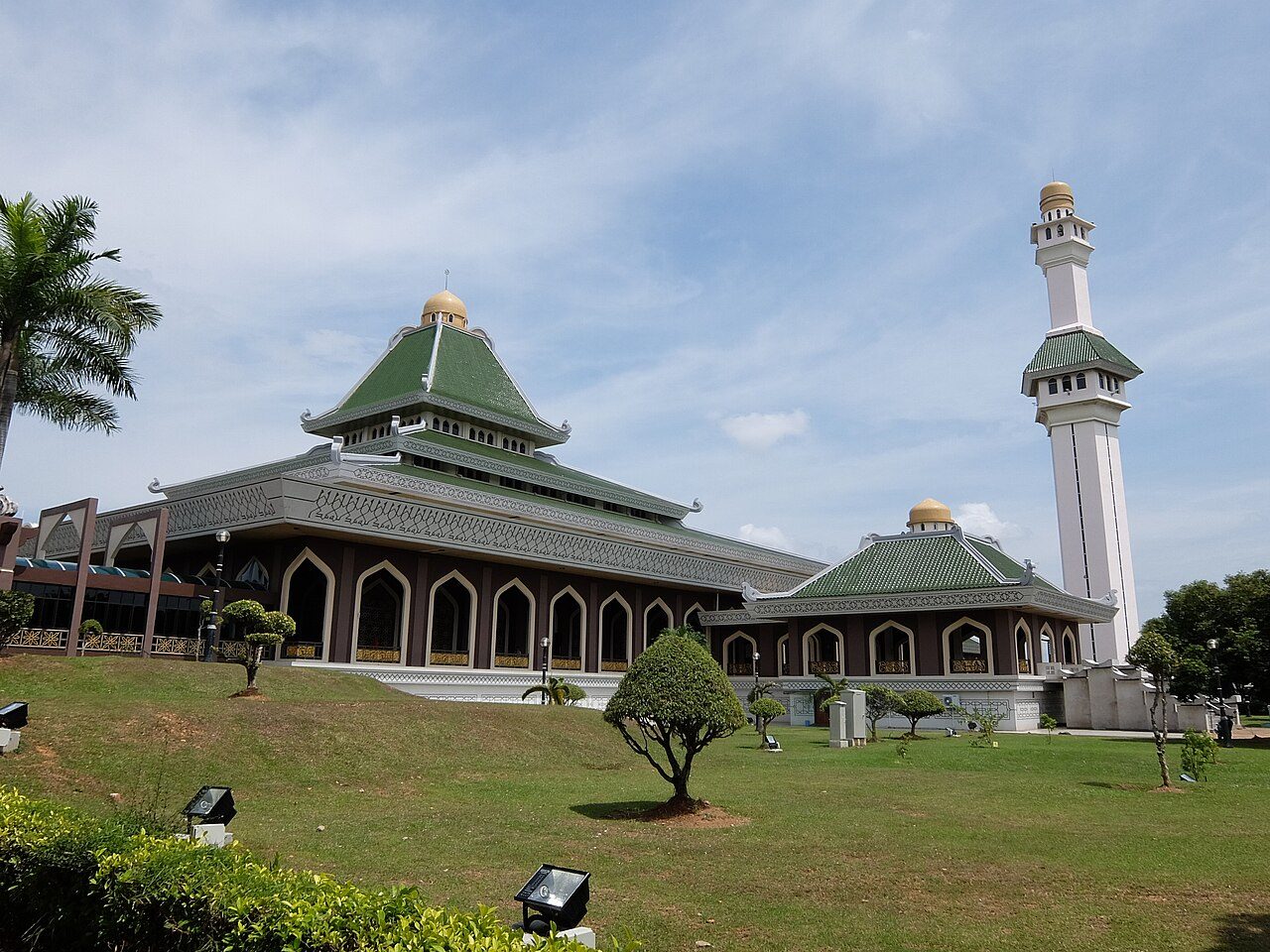 Masjid Al-Azim in Melaka with green tiered roofs, a white minaret and a lawn in front
