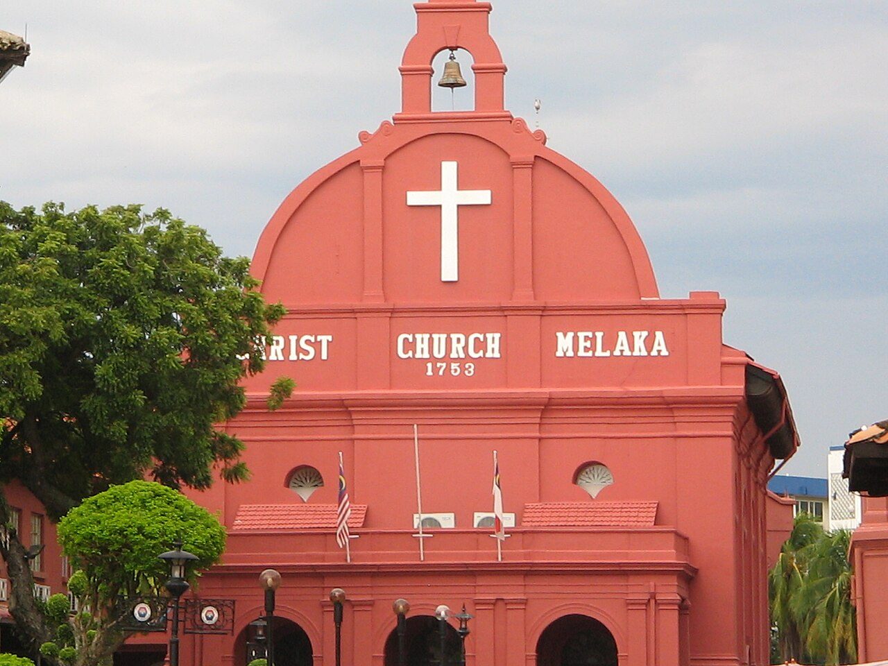 The red facade of Christ Church Melaka with a white cross, a bell and the date 1753