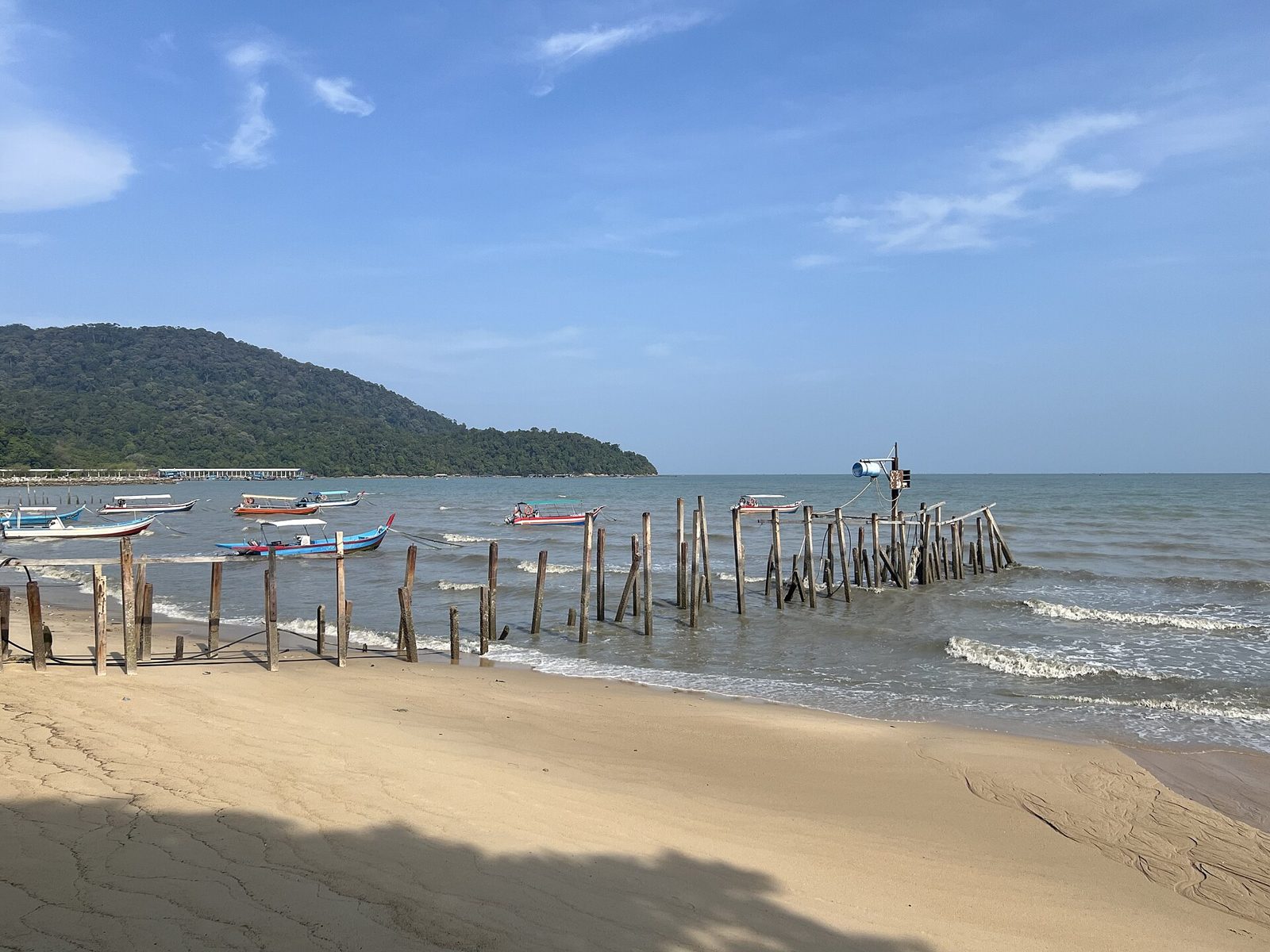 槟城直落巴巴的沙滩，海湾里有老旧的木桩和停泊的渔船