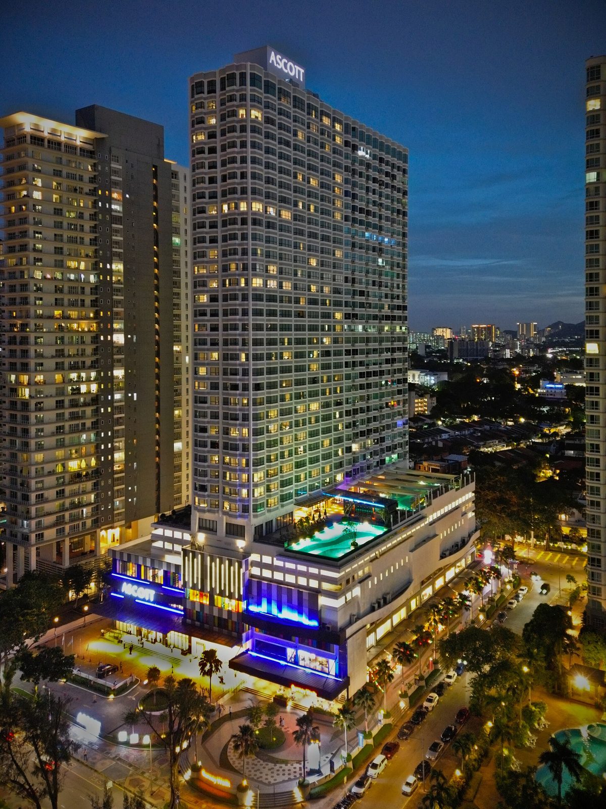 Menara Ascott Gurney Penang pada waktu senja, dengan dek kolam berlampu di atas podium di Gurney Drive