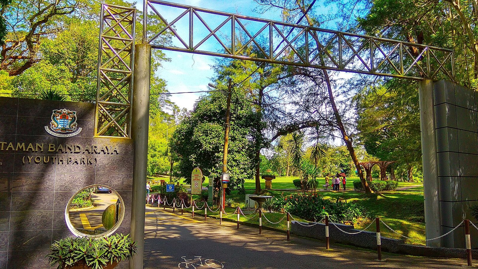 Gerbang masuk dan papan nama Taman Bandaraya (Youth Park) dengan hamparan rumput dan pohon tinggi di belakangnya, Penang