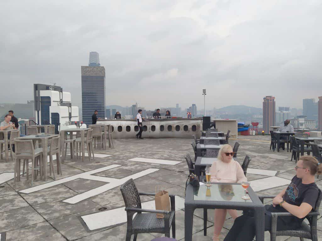 Heli Lounge Bar di helipad terbuka di puncak Menara KH dengan cakrawala KL saat matahari terbenam dan tanpa pagar pembatas