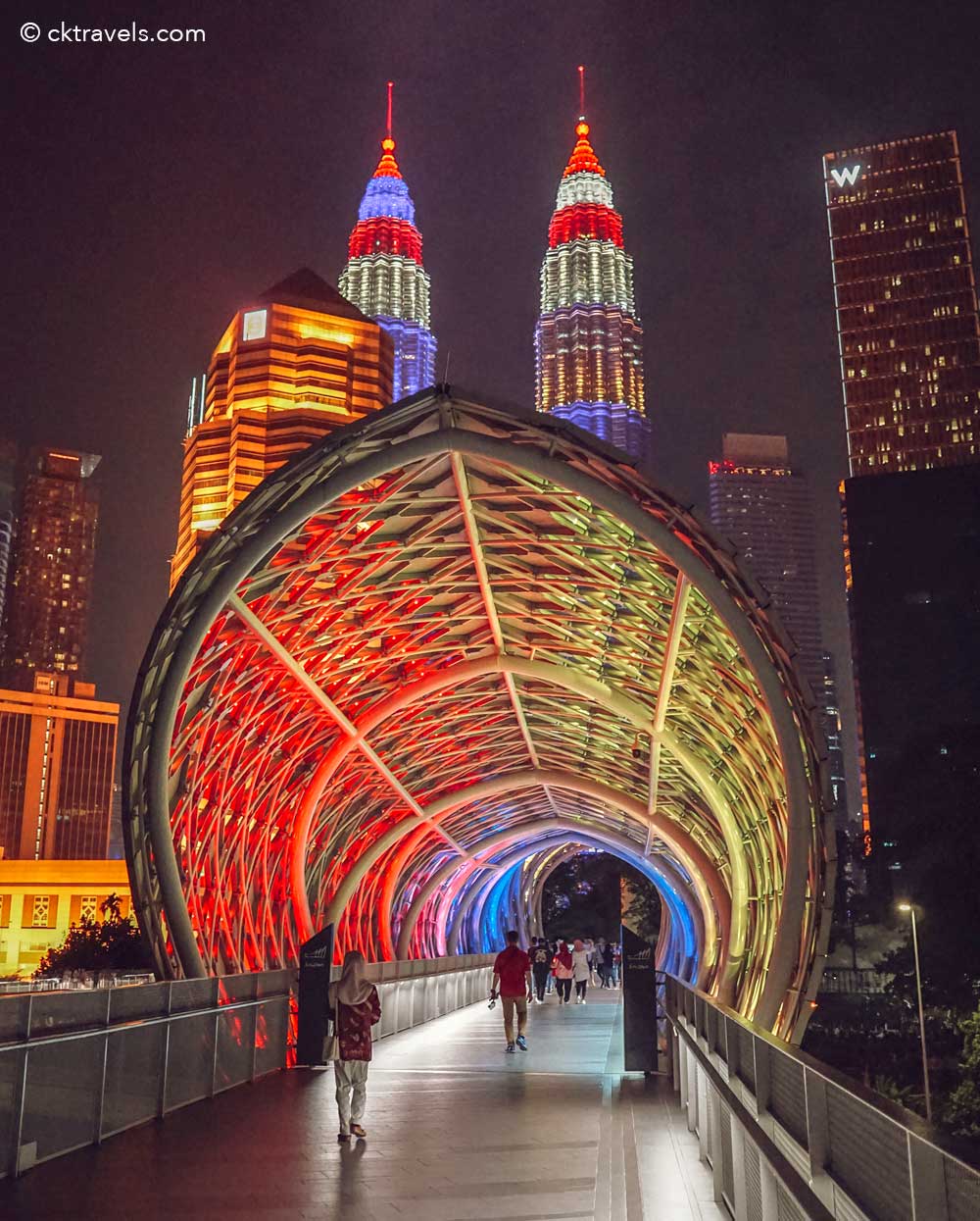 Lengkungan LED berganti warna di Jembatan Saloma pada malam hari dengan latar skyline Kuala Lumpur
