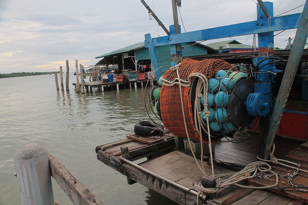 A fishing boat and stilt buildings beside the water at Pulau Ketam