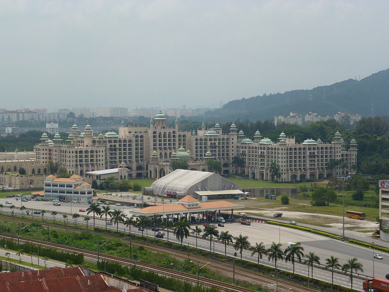 Palace of the Golden Horses, a long cream hotel with green domes and towers, seen across the highway at Mines Resort City