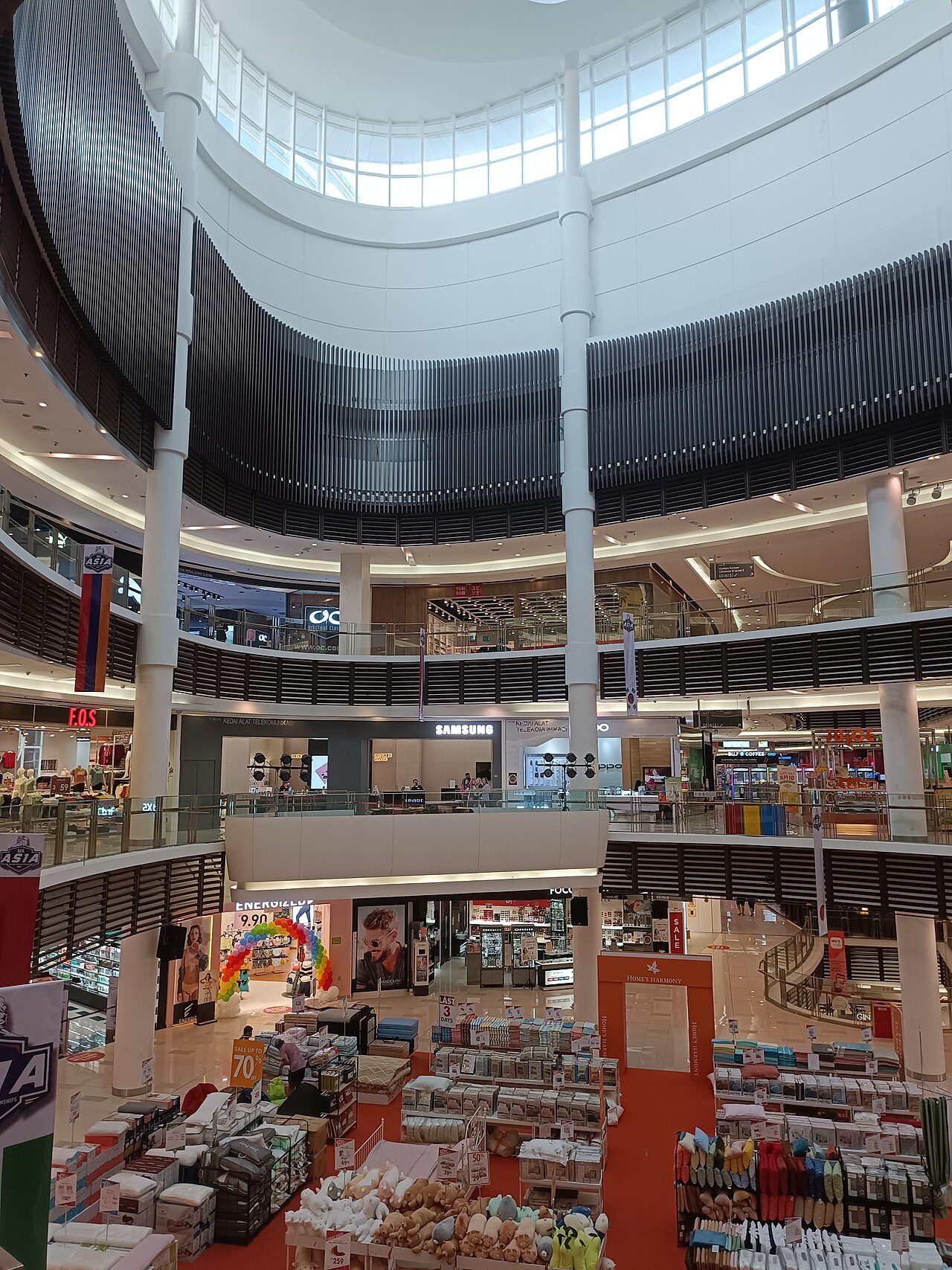 The multi-level atrium of Paradigm Mall in Petaling Jaya under a curved glass roof, with shops on every floor