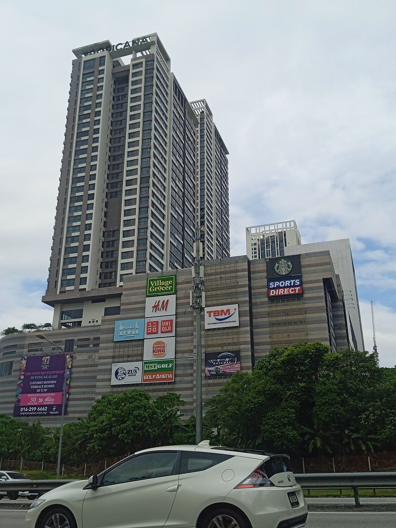 Tropicana Gardens Mall seen from the highway, a low mall block with store signs below a tall residential tower