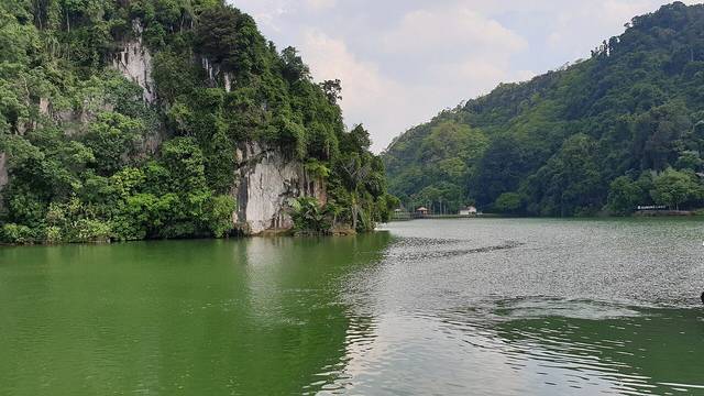 Green lake at Gunung Lang Recreational Park with limestone cliffs rising behind