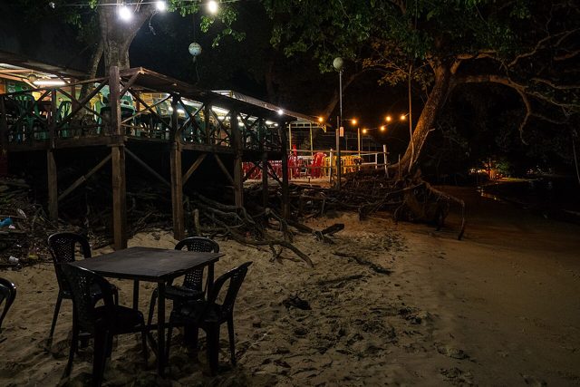 Wooden beachfront eatery with tables on the sand at Teluk Nipah, Pangkor Island, lit at night